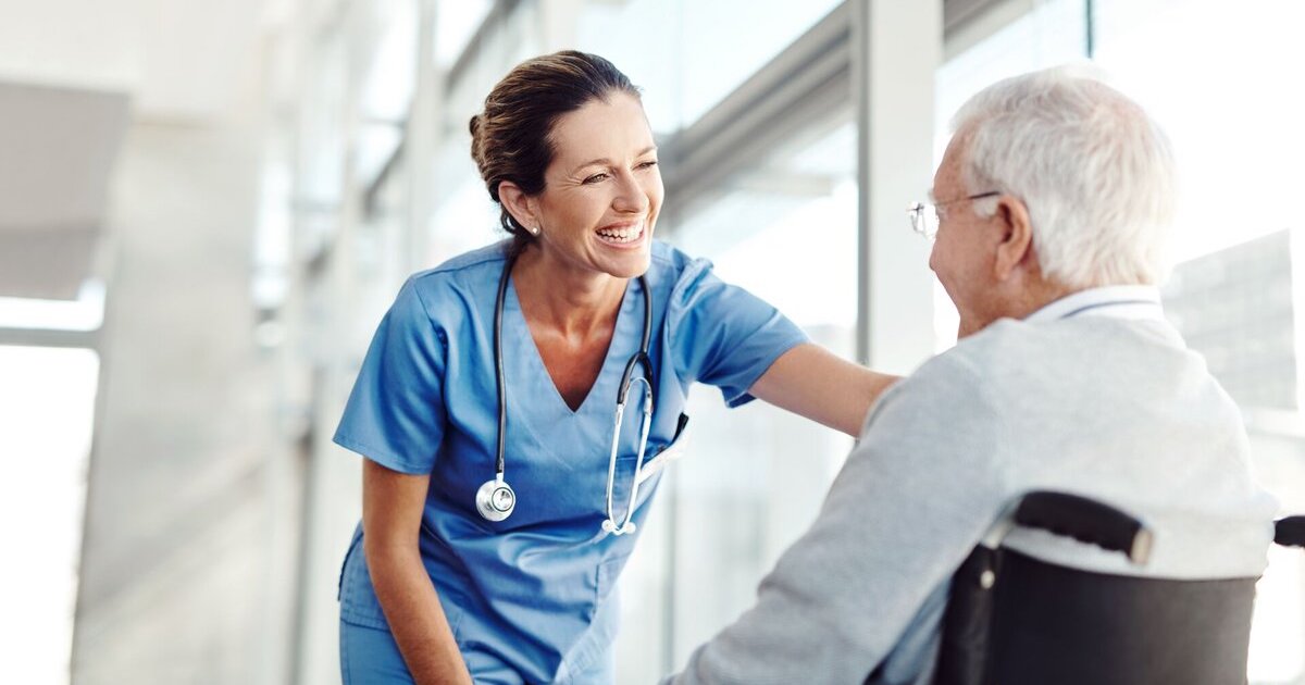 Caregiver and patient in a wheelchair smile at each other