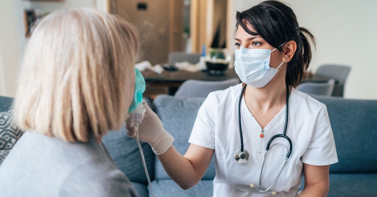 A clinician in a mask checks the oxygen of a patient at a community clinic.