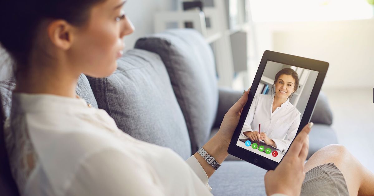 Person sits on couch while having a video visit with a mental health clinician