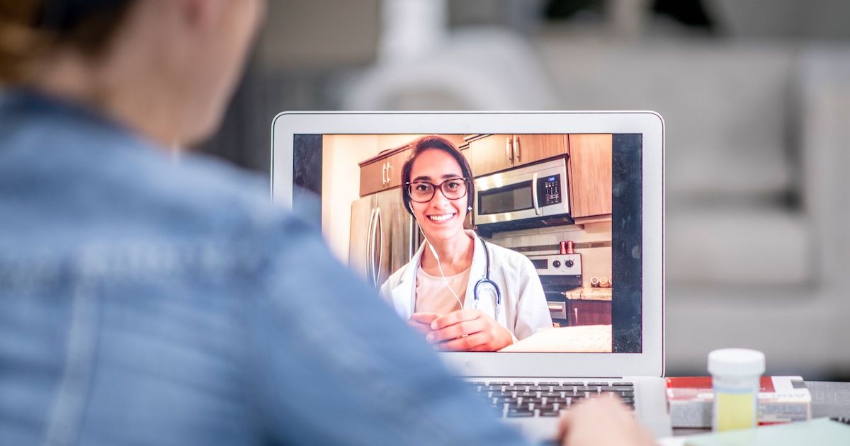 A doctor having a virtual consultation with a patient using a laptop