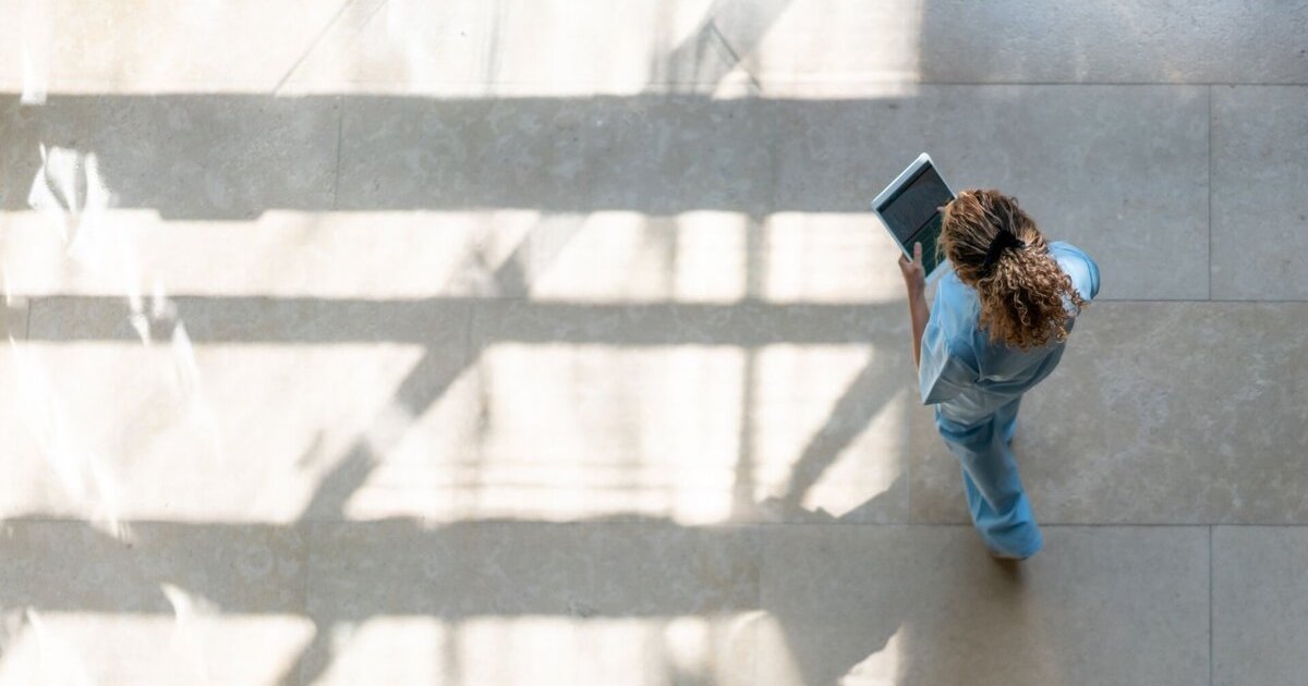 High-angle shot of a nurse using a digital tablet while walking