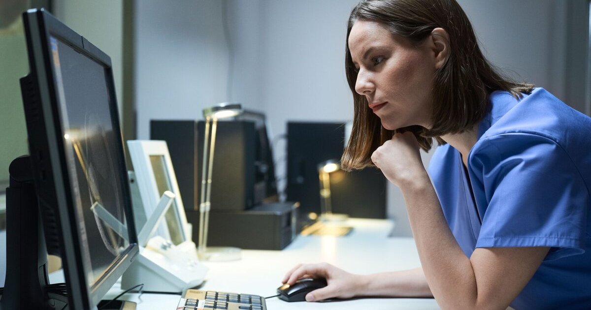 A doctor checking on a patient's file on a desktop computer