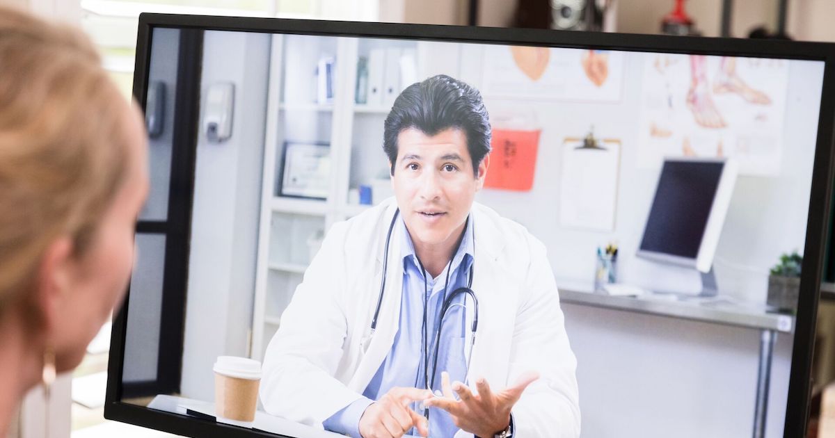 A patient having a virtual consultation with a doctor on a desktop computer
