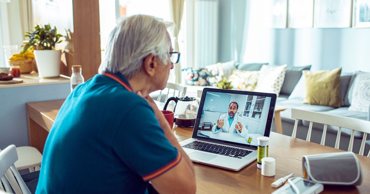 A senior person consulting with a doctor online on a laptop