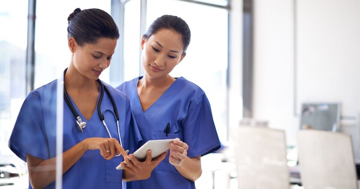 Nurses review a patient record on a digital tablet
