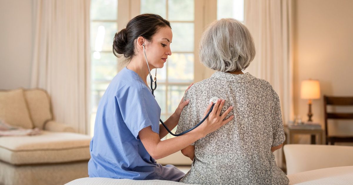 A nurse at home listening to a patient's chest