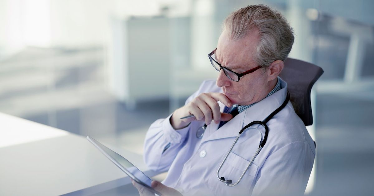 A doctor reading a patient's medical record on a digital tablet