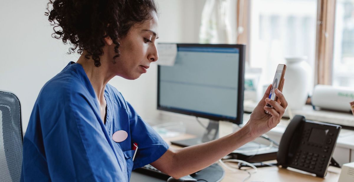 Doctor using a smartphone sitting at a computer desk