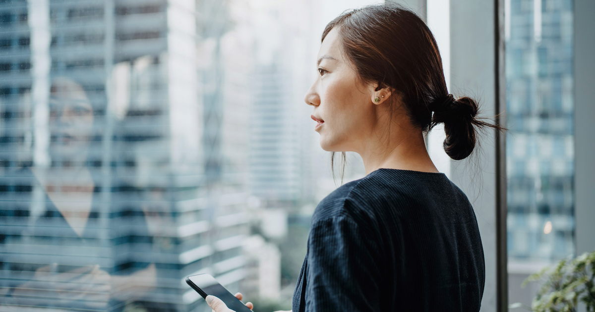 Person with smartphone looking out of a window
