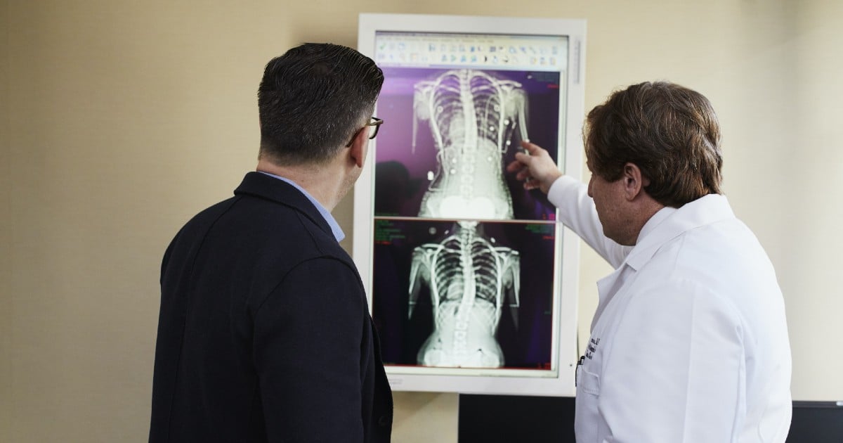 Two people look at an X ray of a ribcage