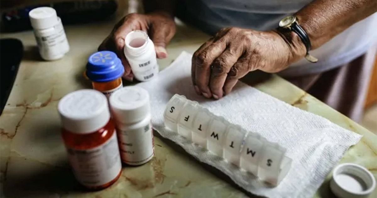 Hands are putting medications in a daily prescription sorting box