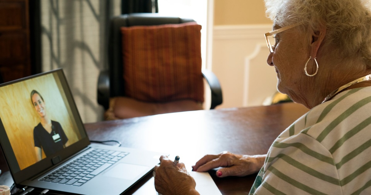 An elderly patient in a virtual consult with a doctor using a laptop computer