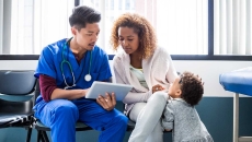 Healthcare worker showing tablet to patient and child