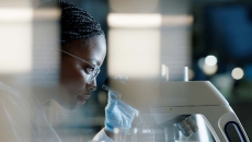 physician looking through microscope for precision medicine