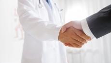A doctor shaking hands with a businessman.