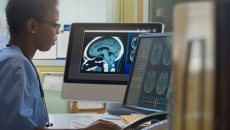 Healthcare worker with MRI image working on a computer