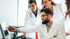 People in medical wear at a screen