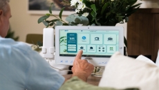 A senior patient using a bedside tablet to order a meal.