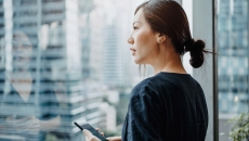 Person with smartphone looking out the window
