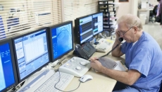 Healthcare working talking on the phone next to computer monitors