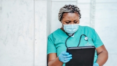Healthcare worker in mask looking at tablet