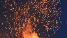 Fire sparks on a night sky represent AI's emergence in clinical care