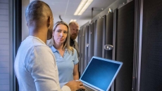 Worker with laptop talking to other IT workers