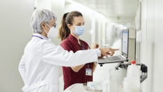 A doctor assisting a staff while using a laptop in the hospital corridor
