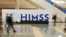 People walk by a HIMSS sign