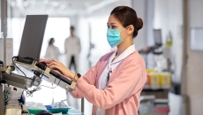 Healthcare worker in mask using laptop terminal