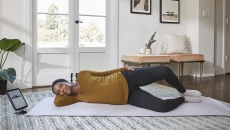 Person lying on exercise mat with tablet on stand