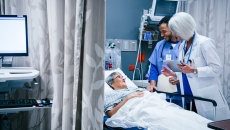 Healthcare workers talking to patient in hospital bed