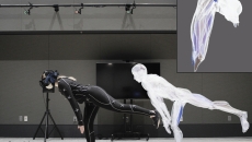 Person in covering suit with electrodes poses, with a duplicate image of the figure nearby
