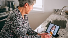 A patient looks at a doctor's face on a tablet screen