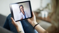 A physician visible on a tablet screen