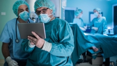 Surgeons looking at a tablet with operating room in background