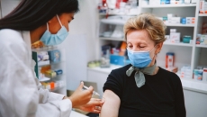 Healthcare worker in mask giving shot to patient in mask