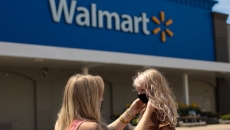 Parent putting mask on their child in front of a Walmart