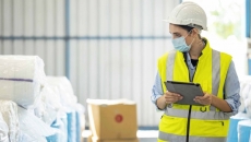 Warehouse worker in a mask with a tablet