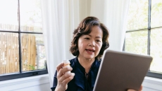 Woman with pill bottle talking into tablet