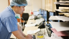 A clinician in scrubs looking at a computer