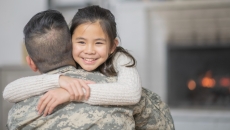 A parent in a military uniform hugging their child