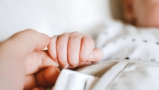 A baby grabbing an adult's finger