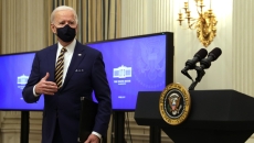 President Joe Biden stands in front of monitors