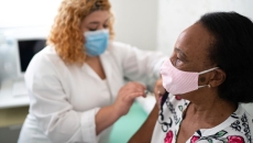 Healthcare worker in mask giving patient in mask vaccine