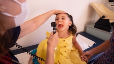 A clinician looking inside a child's mouth at a medical appointment