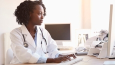Person wearing stethoscope at a computer
