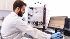 A person in lab wear sits at a computer