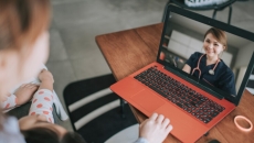 A person in scrubs appears on a laptop screen