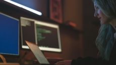 A person at a computer sitting in a darkened room